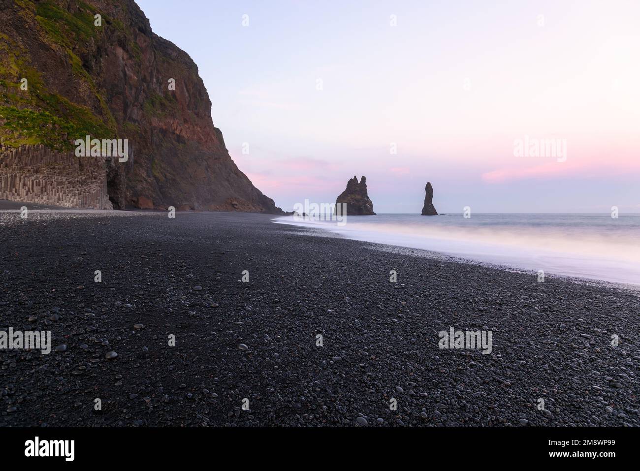 Sea stacks along a black pebble beach in Iceland under midnight sun in summer Stock Photo
