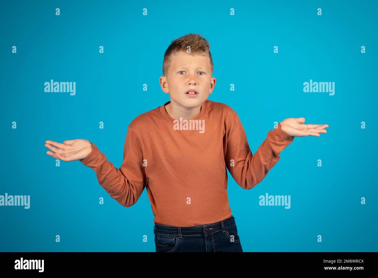 I Don't Know. Doubtful Preteen Boy Shrugging Shoulders And Spreading Arms Stock Photo