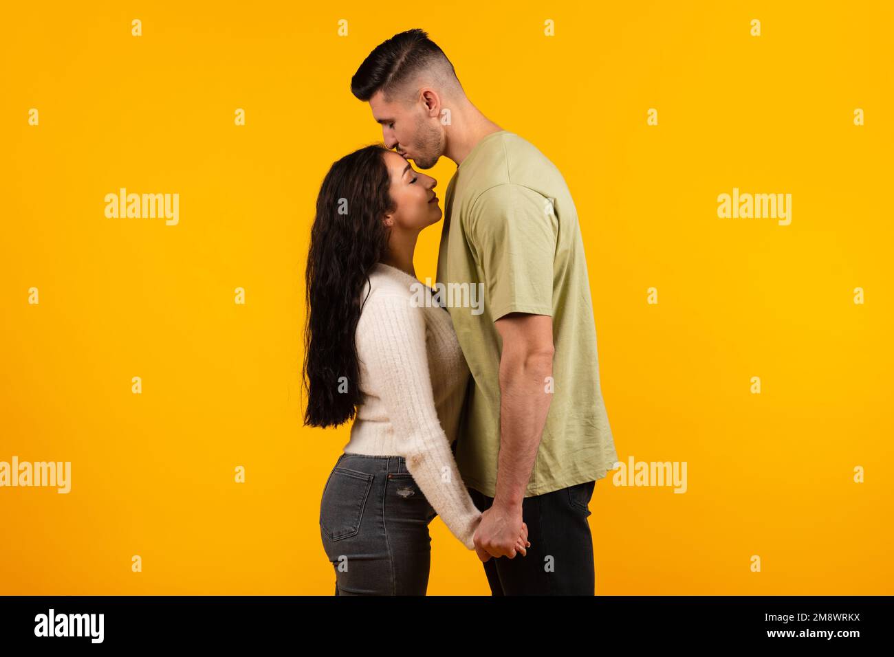 Cheerful millennial arab tall husband kissing wife on forehead, couple enjoy free time and tender moment Stock Photo