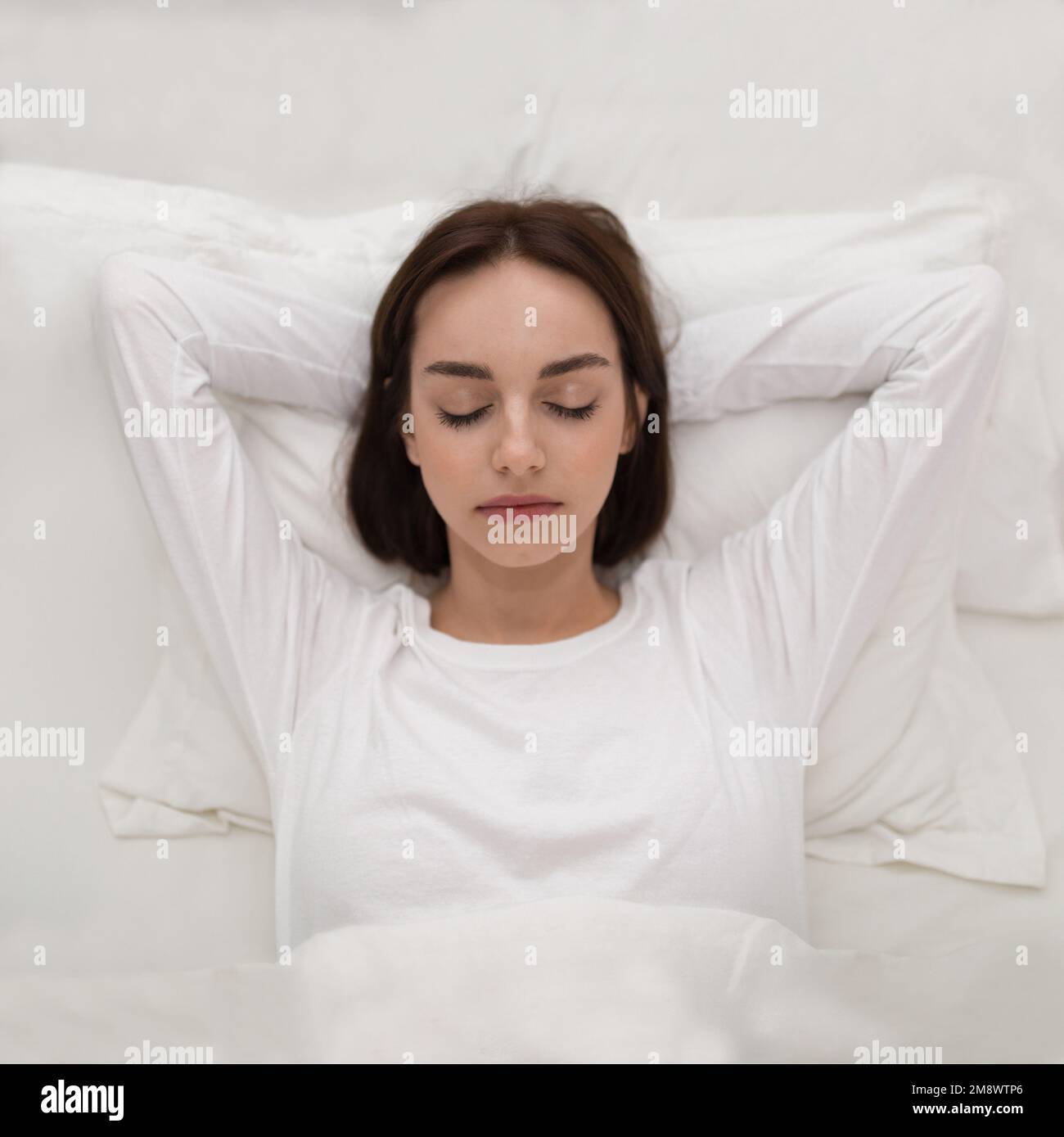 Top view of young woman sleeping with hands under head Stock Photo