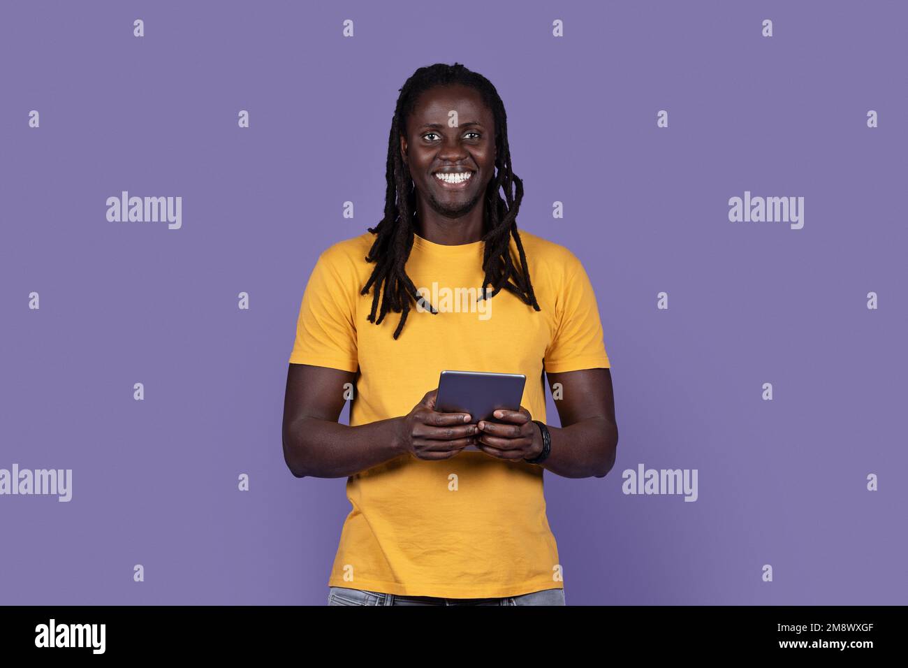 Happy stylish young black guy using digital pad on purple Stock Photo