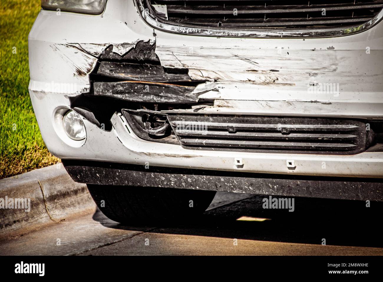 Wrecked white SUV front with outside shell of vehicle torn off to reveal what is underneath-parked by curb and grass -Closeup Stock Photo