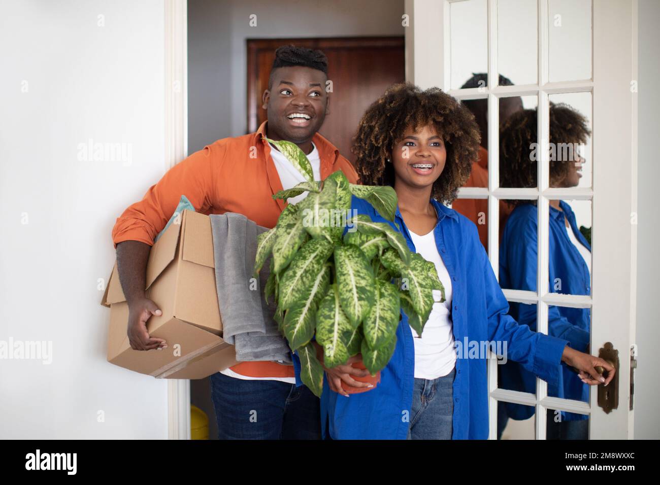 Excited black couple entering their apartment and carrying boxes with belongings Stock Photo