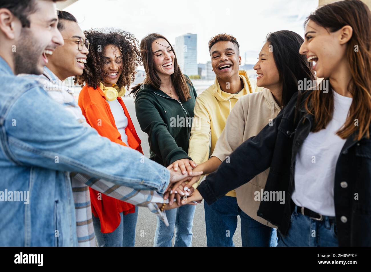 Diverse teenage student friends stacking hands showing teamwork and cooperation Stock Photo