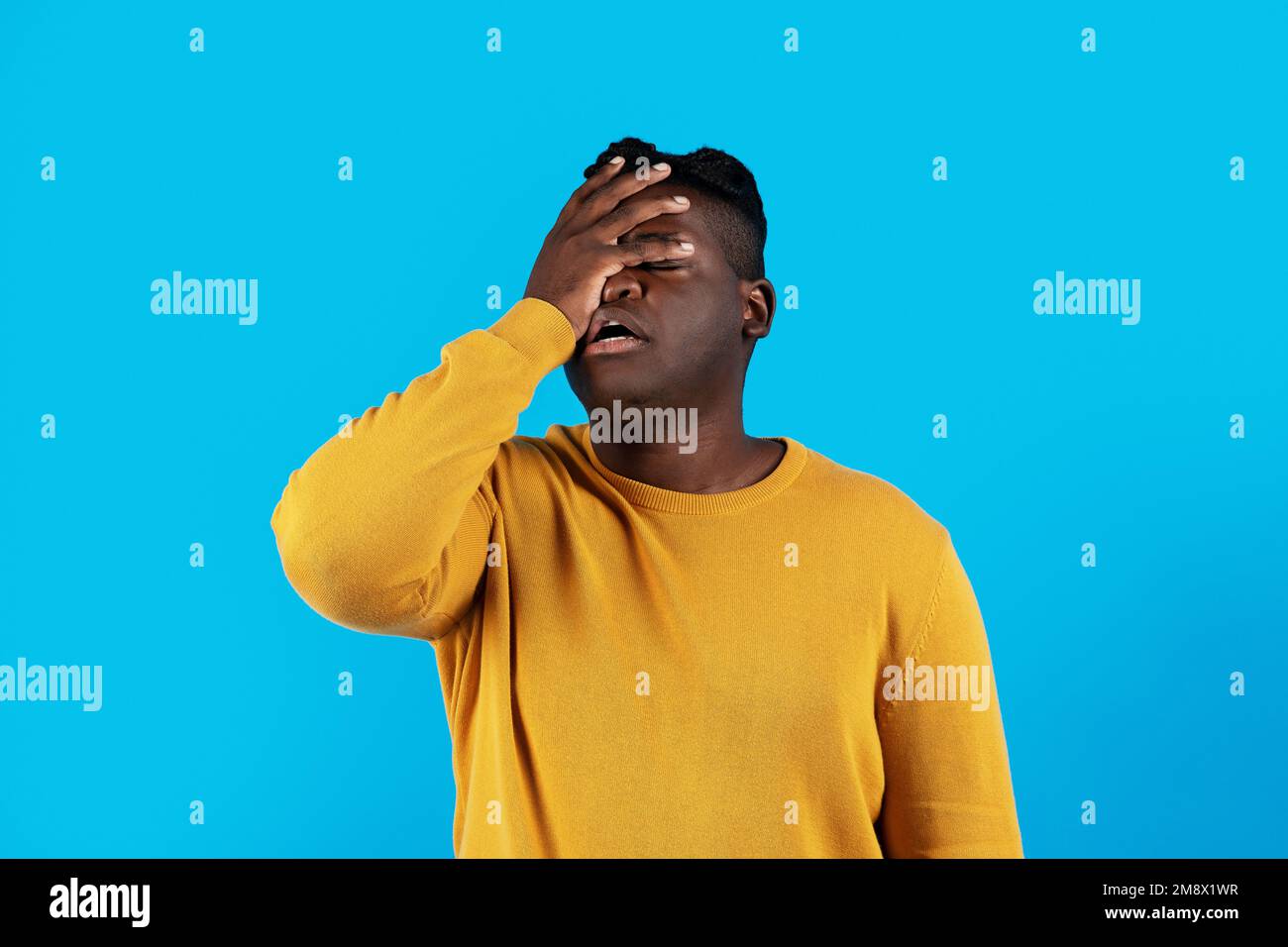 Young Black Man Doing Facepalm Gesture While Standing Isolated Over Blue Background Stock Photo