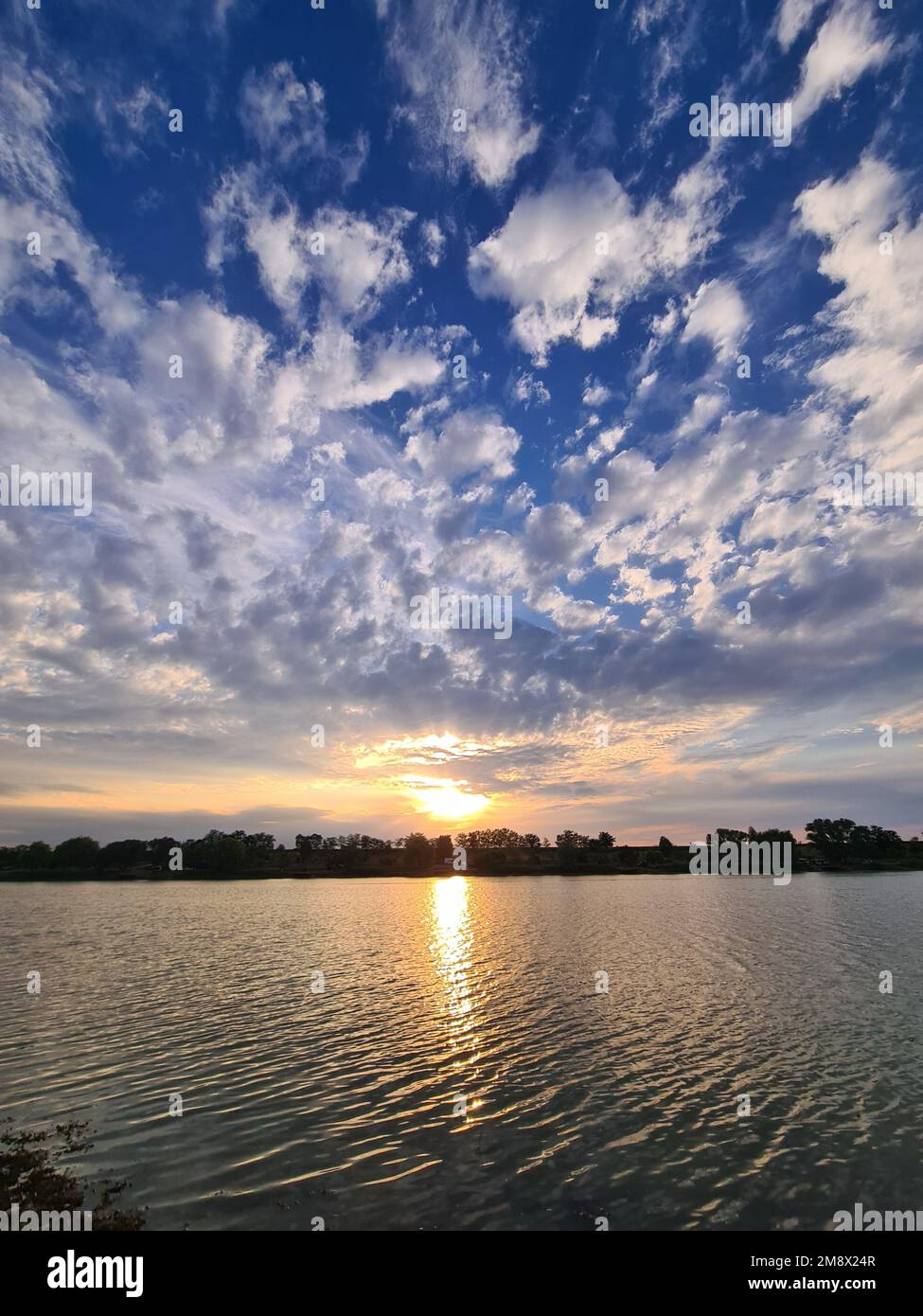 A landscape of the sunset scene over a lake under blue cloudy sky Stock ...