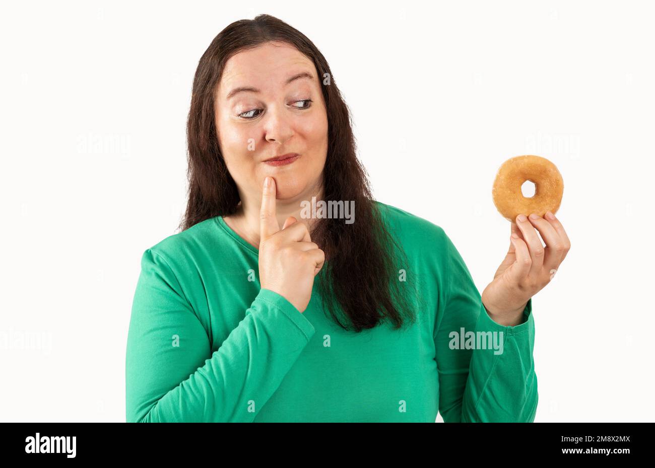 Adult woman over white grunge wall eating sugar donut serious face thinking about question, very confused idea Stock Photo