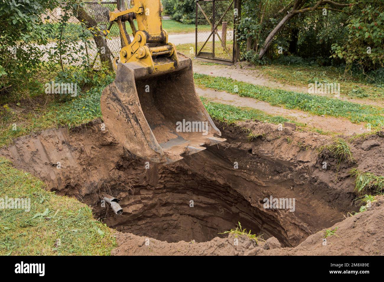 A bucket of excavator over a large deep pit in the ground. Construction