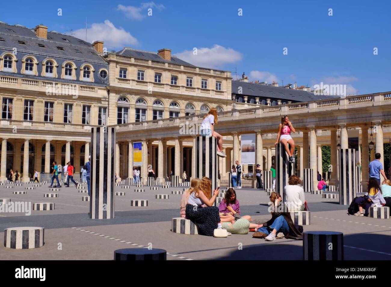 Paris: People enjoying the Colonnes de Buren (Les Deux Plateaux) by Daniel Buren in Cour d'Honneur of the Palais Royal, Paris, France Stock Photo