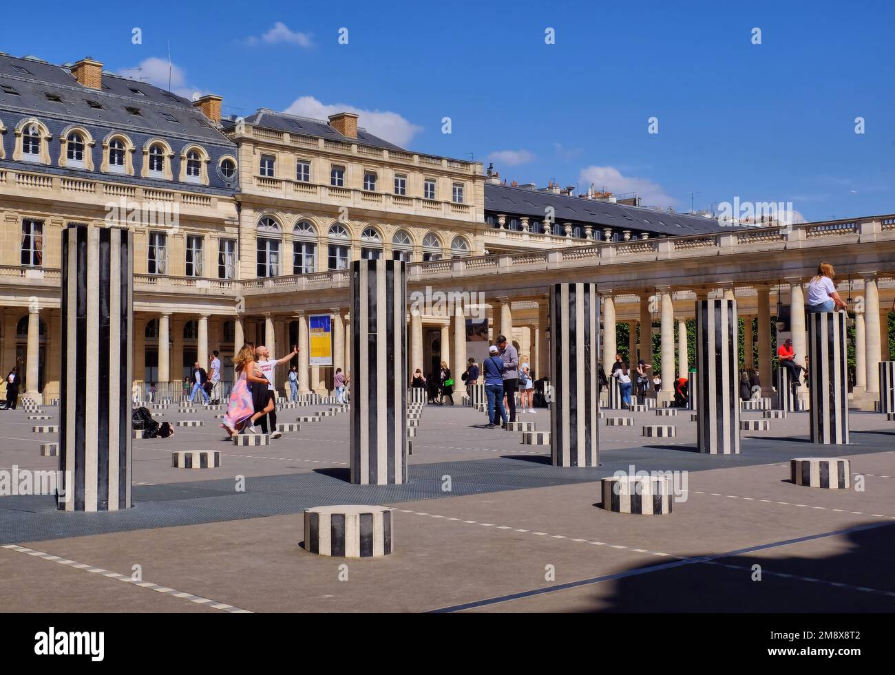 Paris: People enjoying the Colonnes de Buren (Les Deux Plateaux) by Daniel Buren in Cour d'Honneur of the Palais Royal, Paris, France Stock Photo