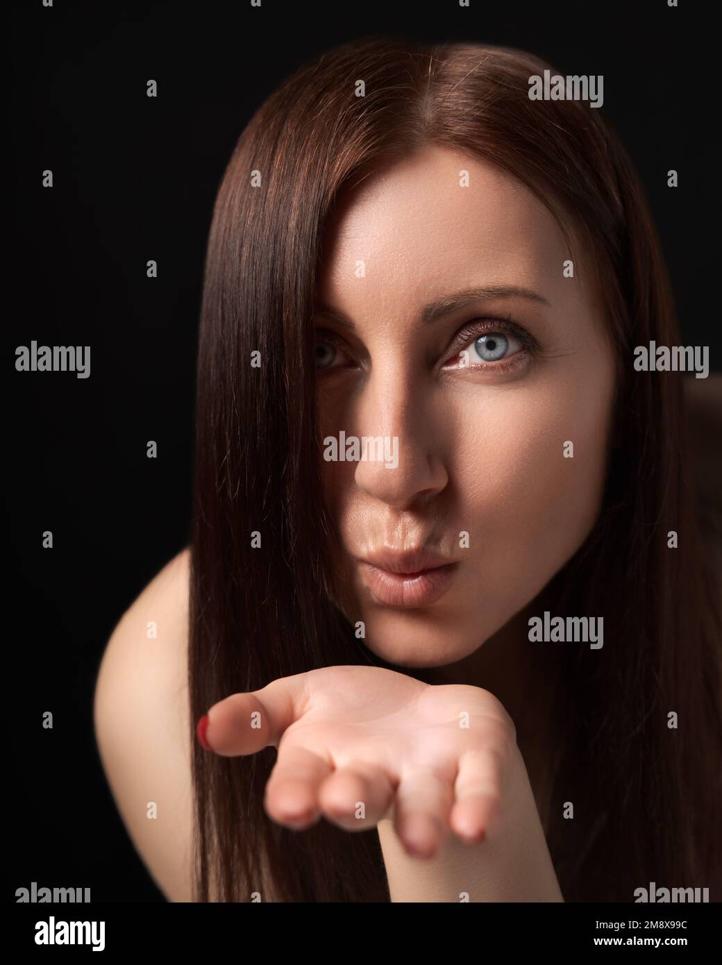 Woman blowing lips sending air kisses over palm to boyfriend, flirting - just for you. 40-year-old Caucasian woman with long hair showing love Stock Photo
