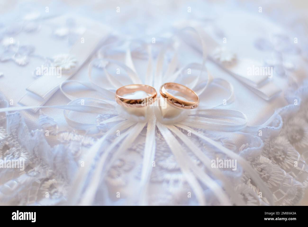 pair of gold wedding traditional rings on a white lace cushion on marriage registration Stock Photo