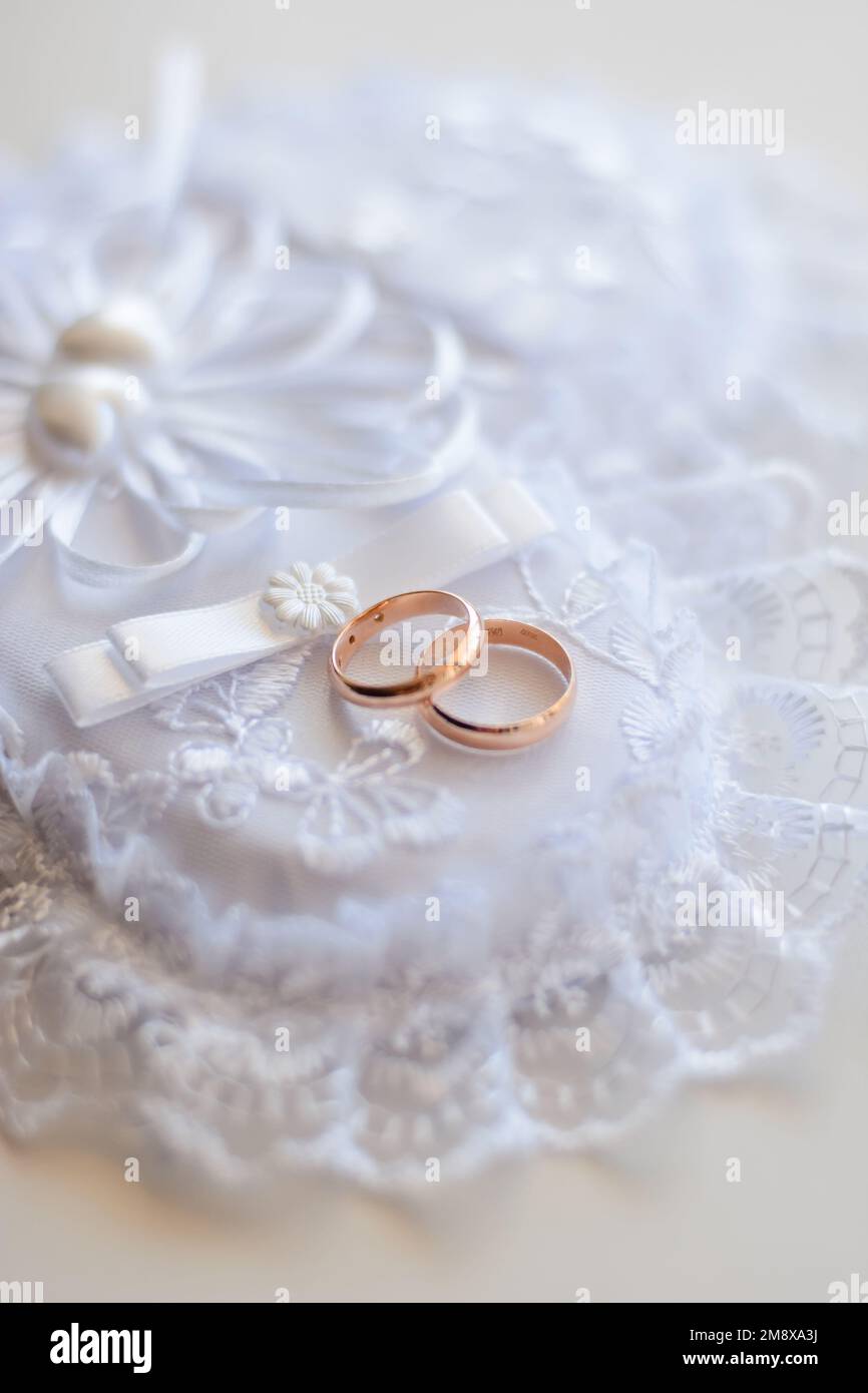 pair of gold wedding traditional rings on a white lace cushion on marriage registration Stock Photo