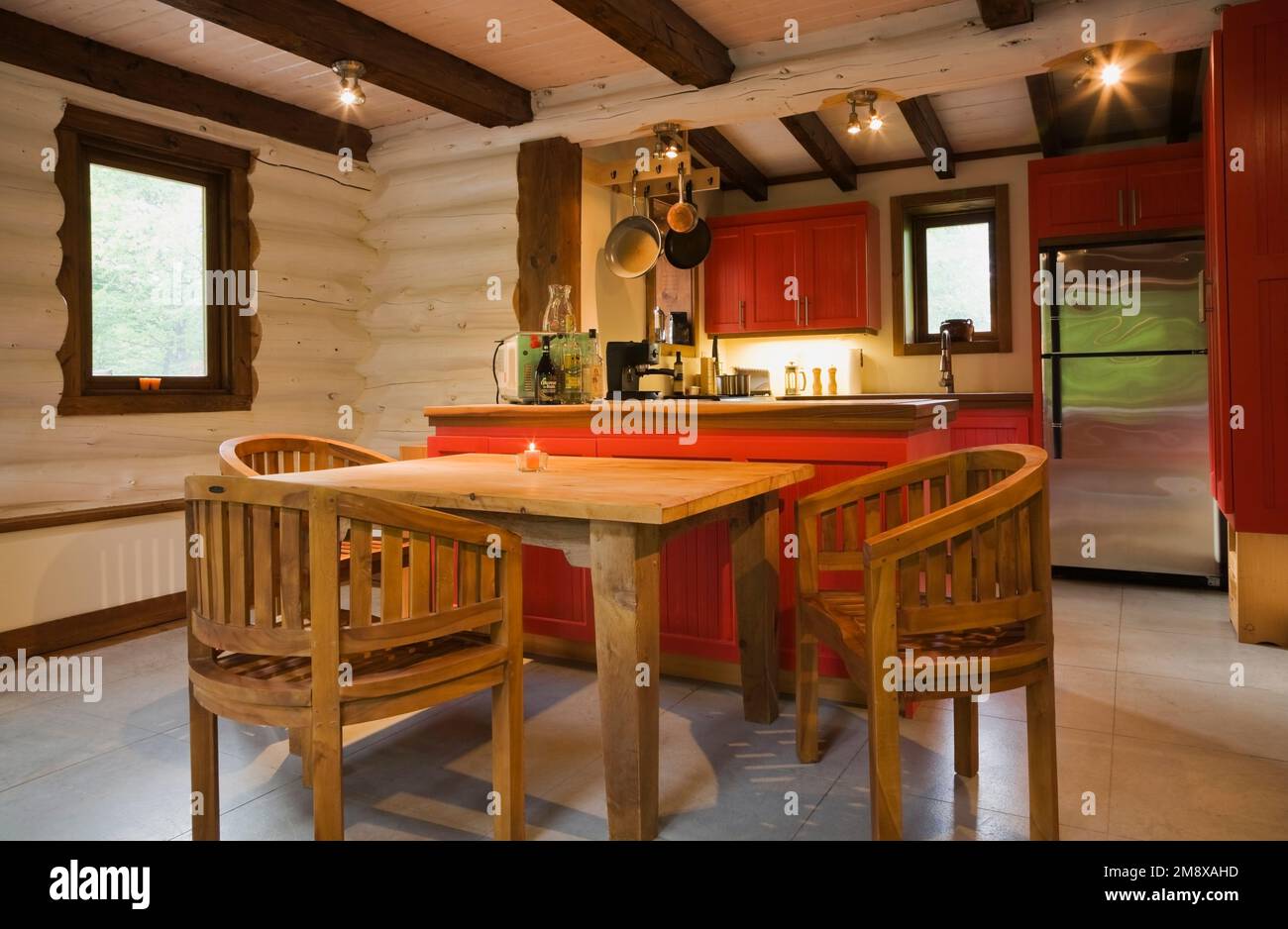 Wooden breakfast table with round back chairs and view of kitchen with red wooden on