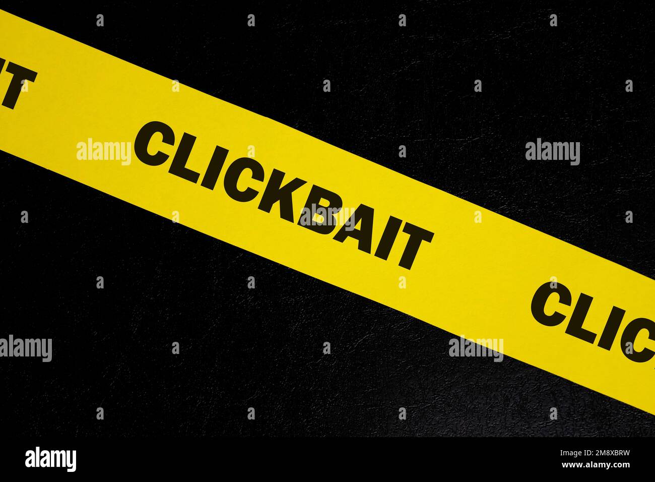 Clickbait scam alert, caution and warning concept. Yellow barricade tape with word clickbait in dark black background. Stock Photo