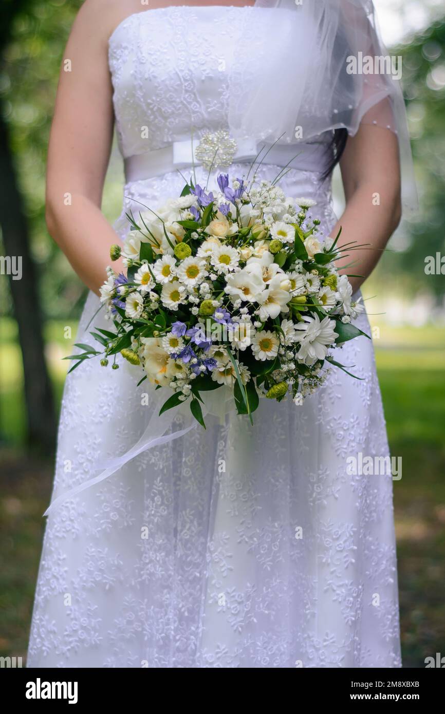 wedding flower bouquet in the hands of the bride in a white dress close ...