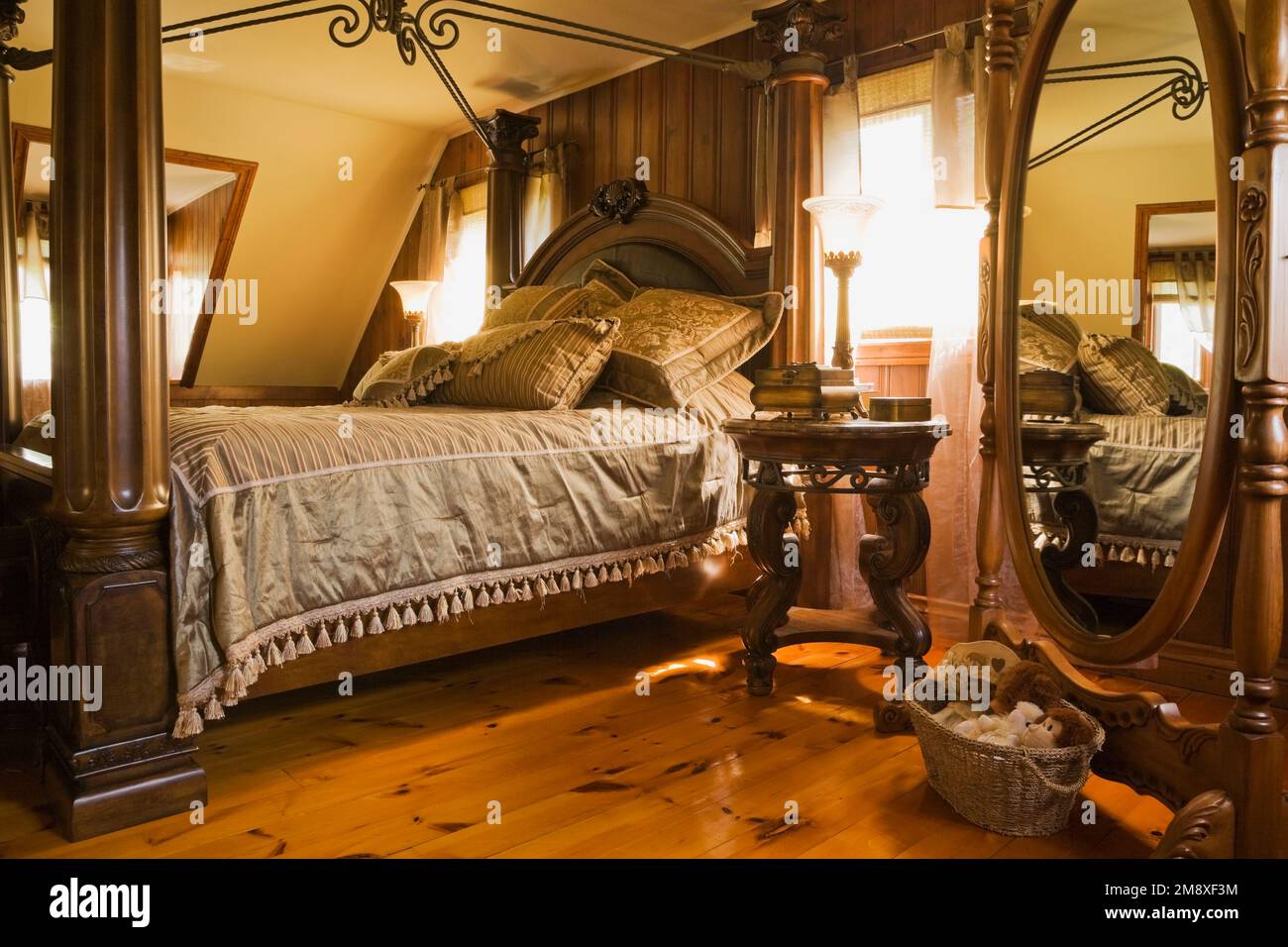 Antique king size canopy bed and oval mirror in master bedroom on