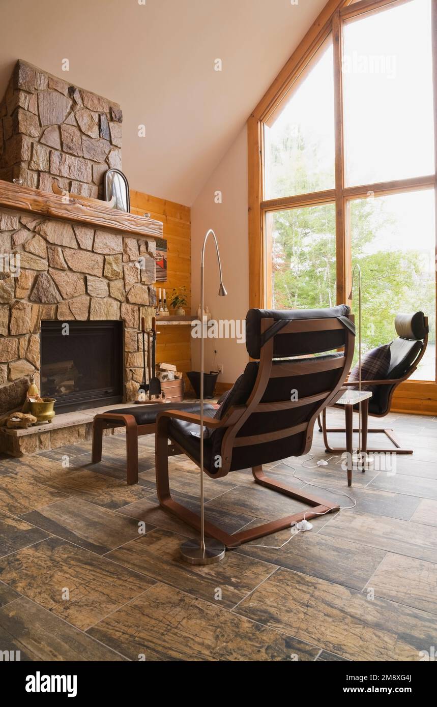 Wooden black leather armchairs in front of natural stone fireplace in