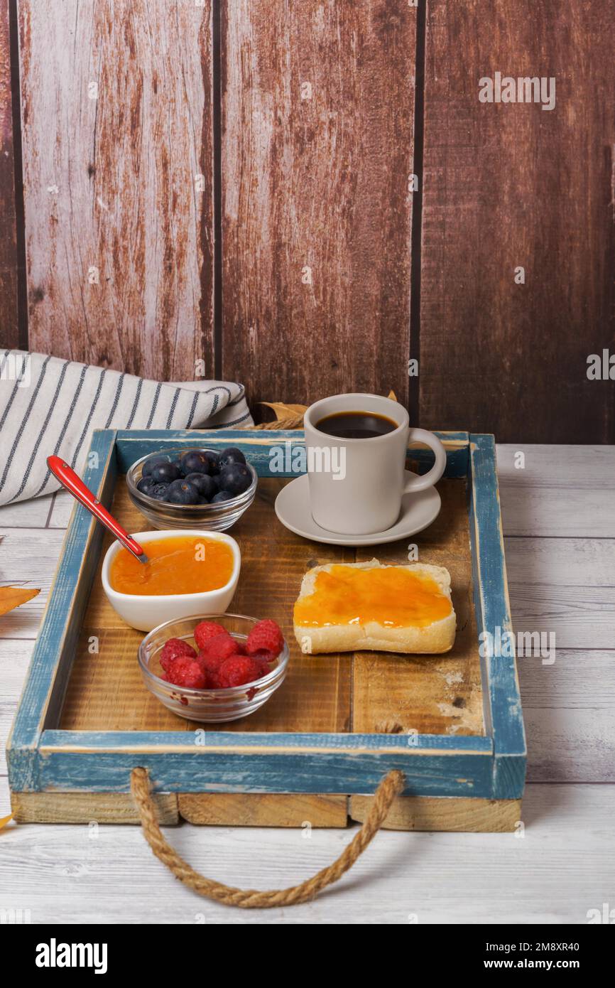Healthy breakfast on a wooden tray, homemade jam, red fruits and coffee ...