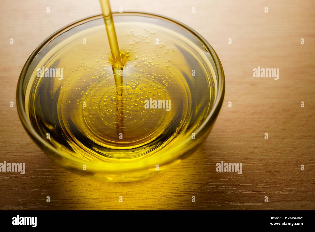 Close-up of a glass cup with extra virgin olive oil with bubbles on a ...