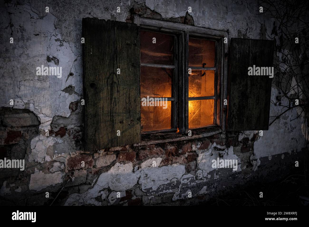 Old decayed wooden window on old house facade in candlelight ...