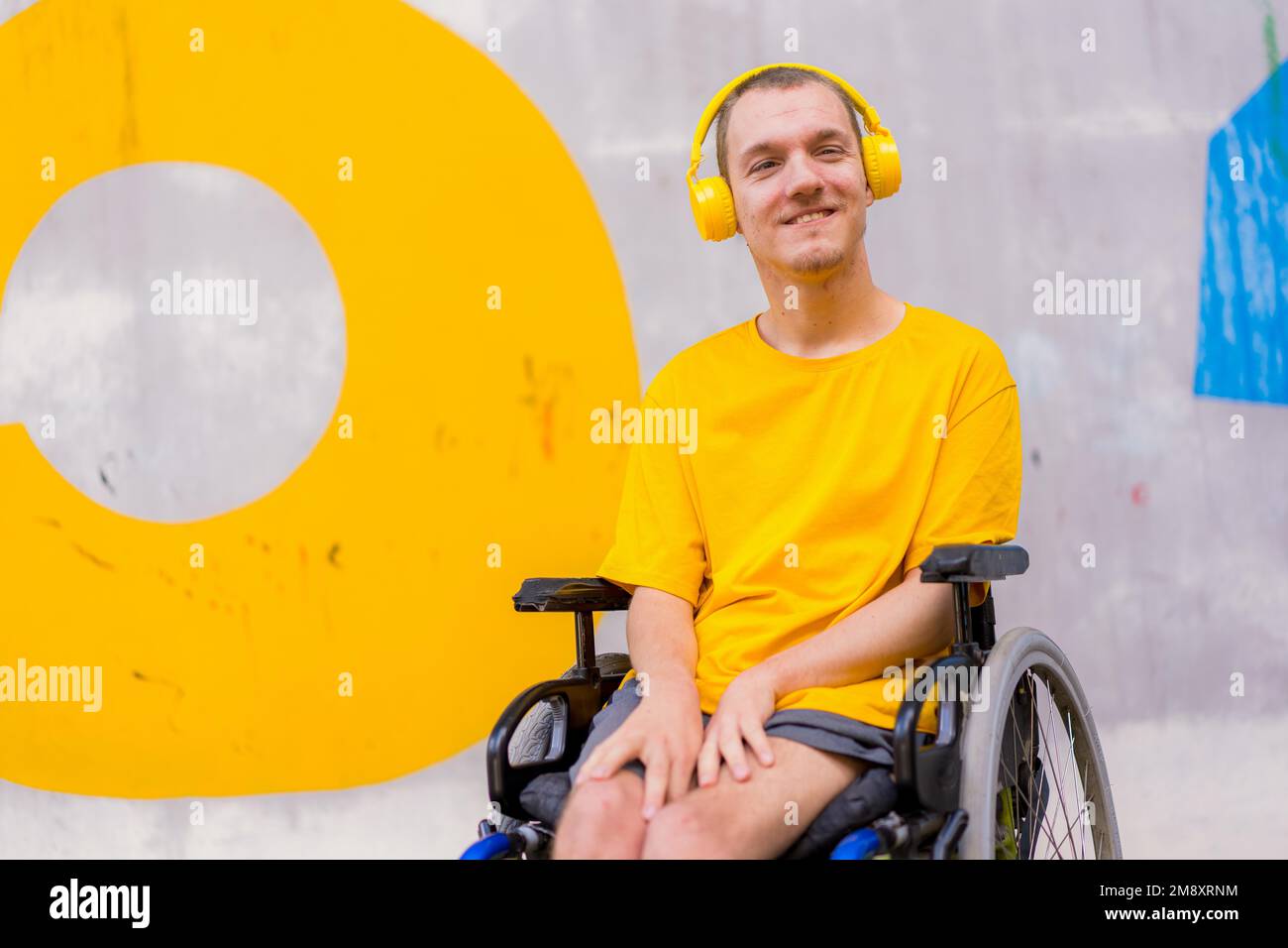 Disabled person in wheelchair listening to music, smiling Stock Photo