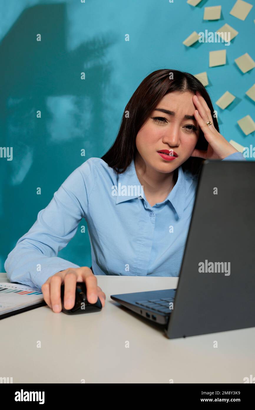 Overworked asian woman having a headache while working late in the