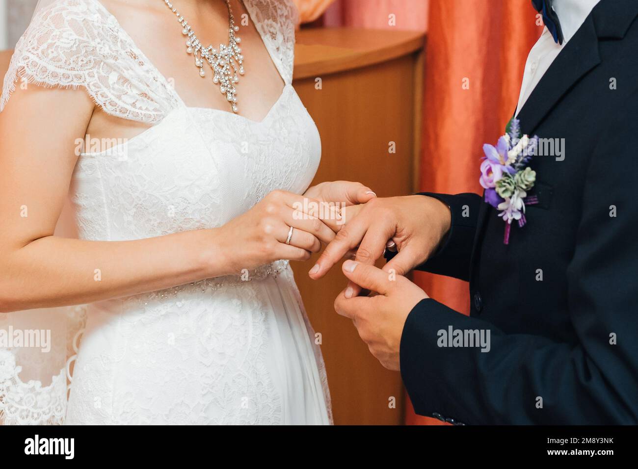 bride puts a gold wedding ring on the finger of the groom. Traditional ...