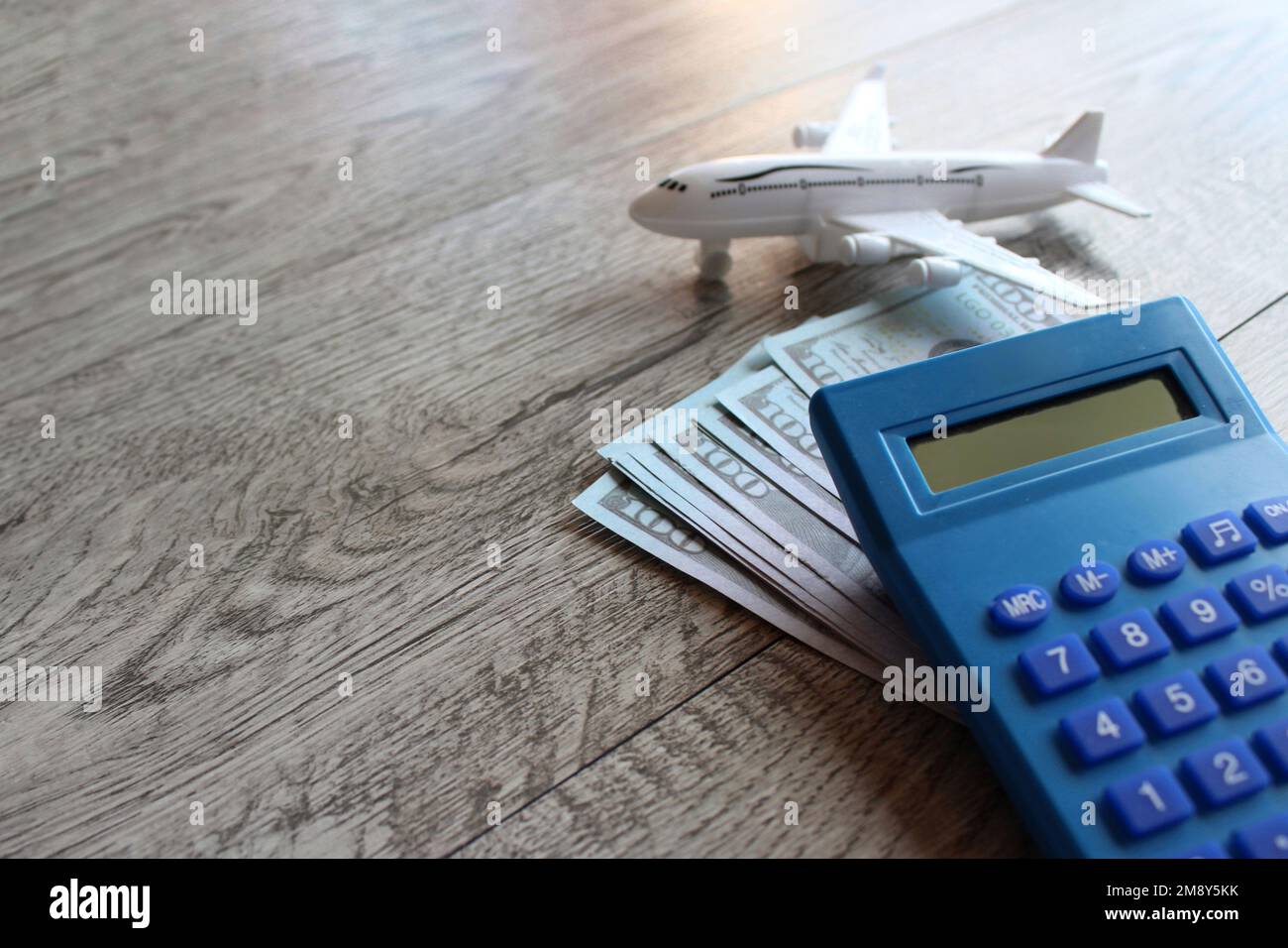 Toy plane, money and calculator on wooden table with copy space. Travel and transportation concept Stock Photo