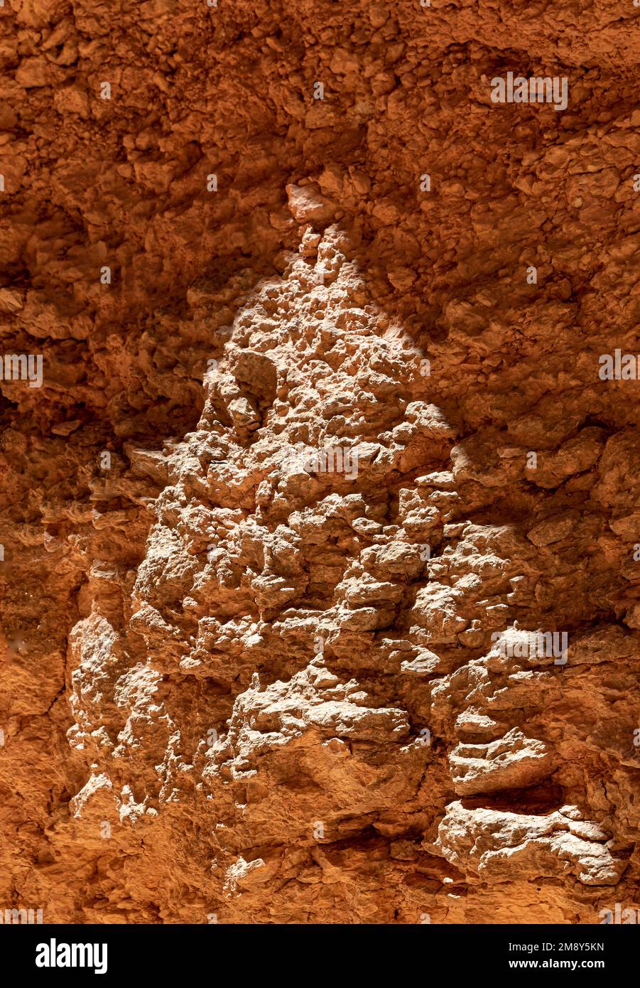 Side light illuminates the surface edges of a rock wall and the space