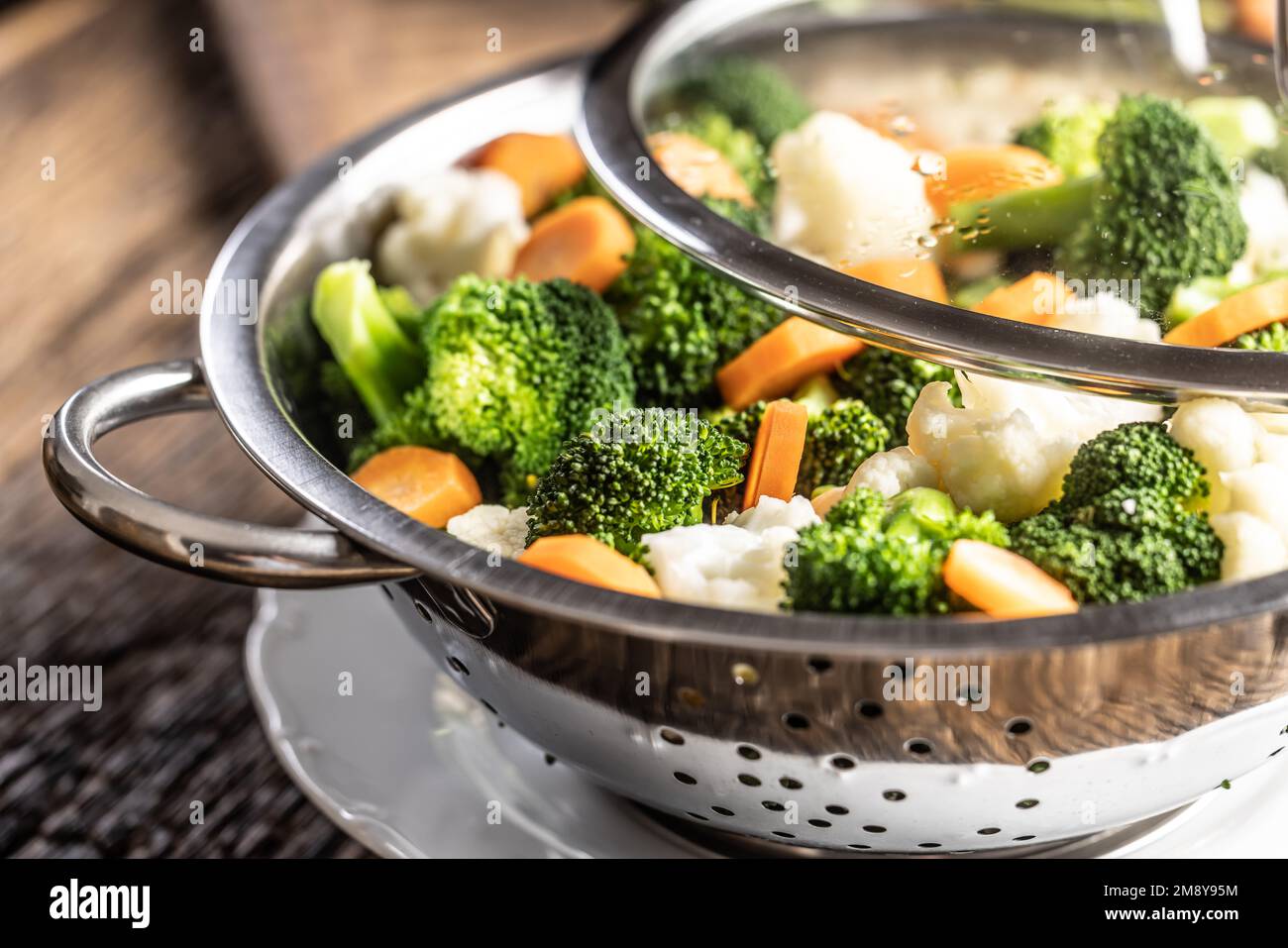 Steamed broccoli, carrots and cauliflower in a stainless steel steamer