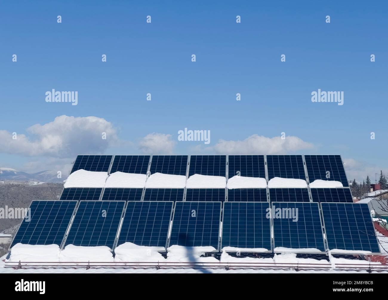 Blue Solar panel over blue sky, sun and clouds. Solar cell panels covered vith snow pattern for sustainable energy. Renewable solar energy. Alternativ Stock Photo