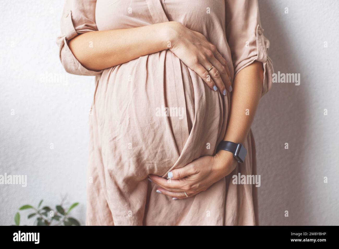 pregnant woman's belly closeup. hands hugging belly. Concept of maternal health. Stock Photo