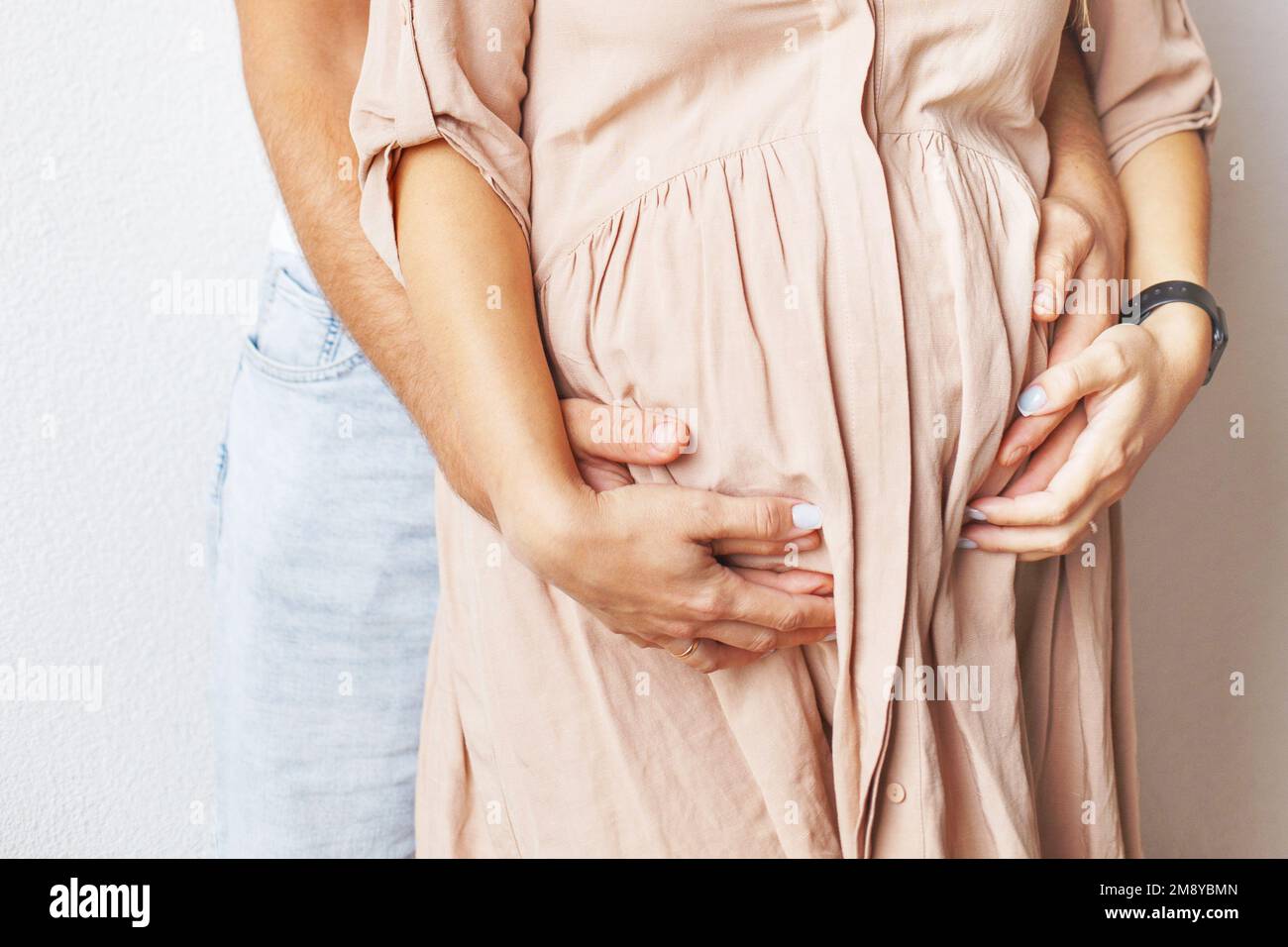 Young pregnant woman and husband hugging her belly close Stock Photo ...