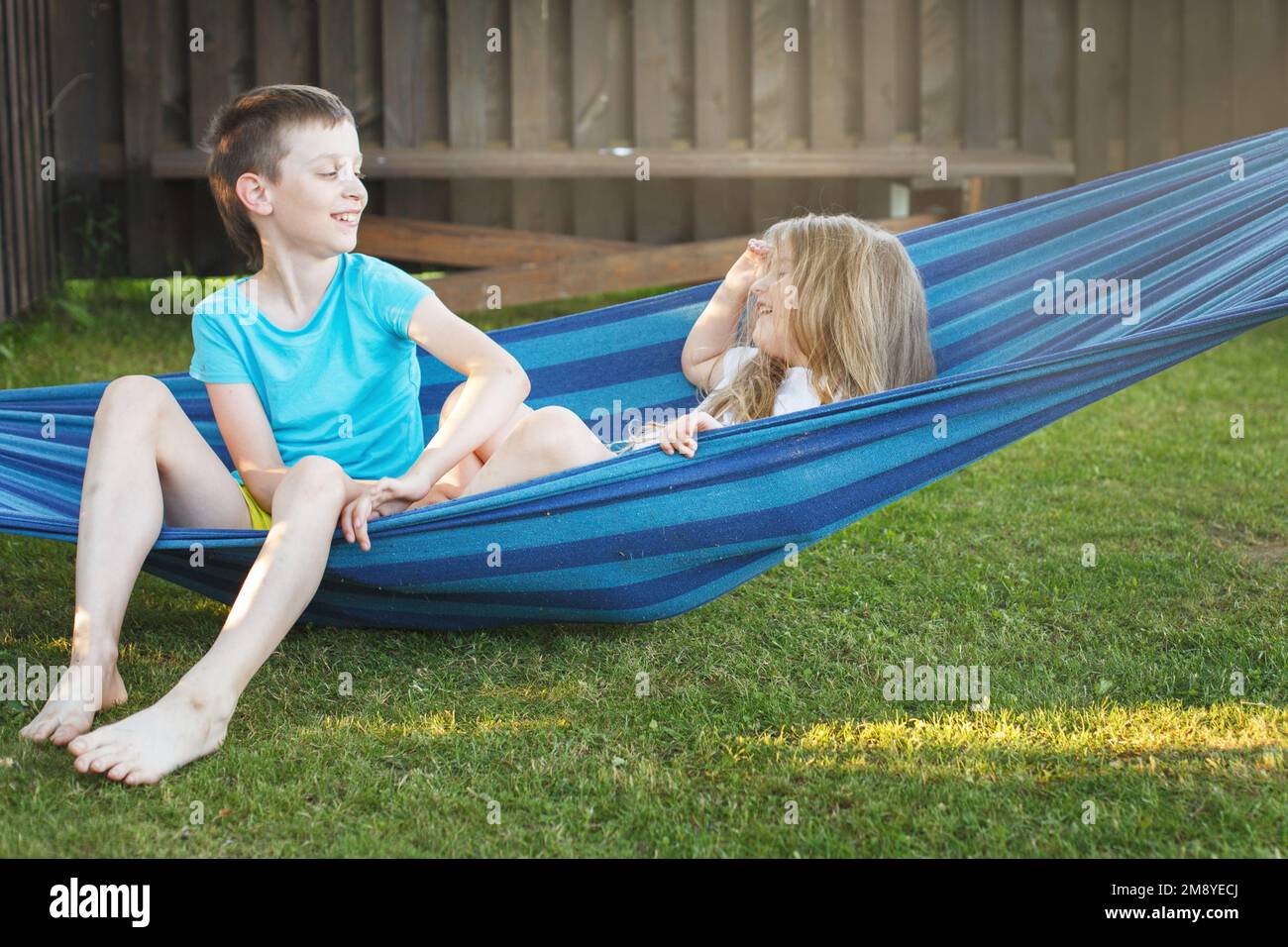 children brother and sister play in the garden on a hammock. Stock Photo
