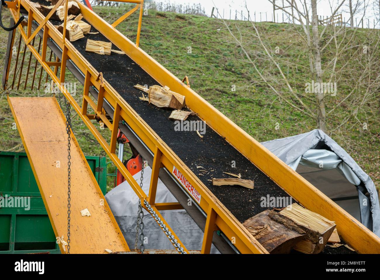Log splitter conveyor with split timber and danger keep clear sign
