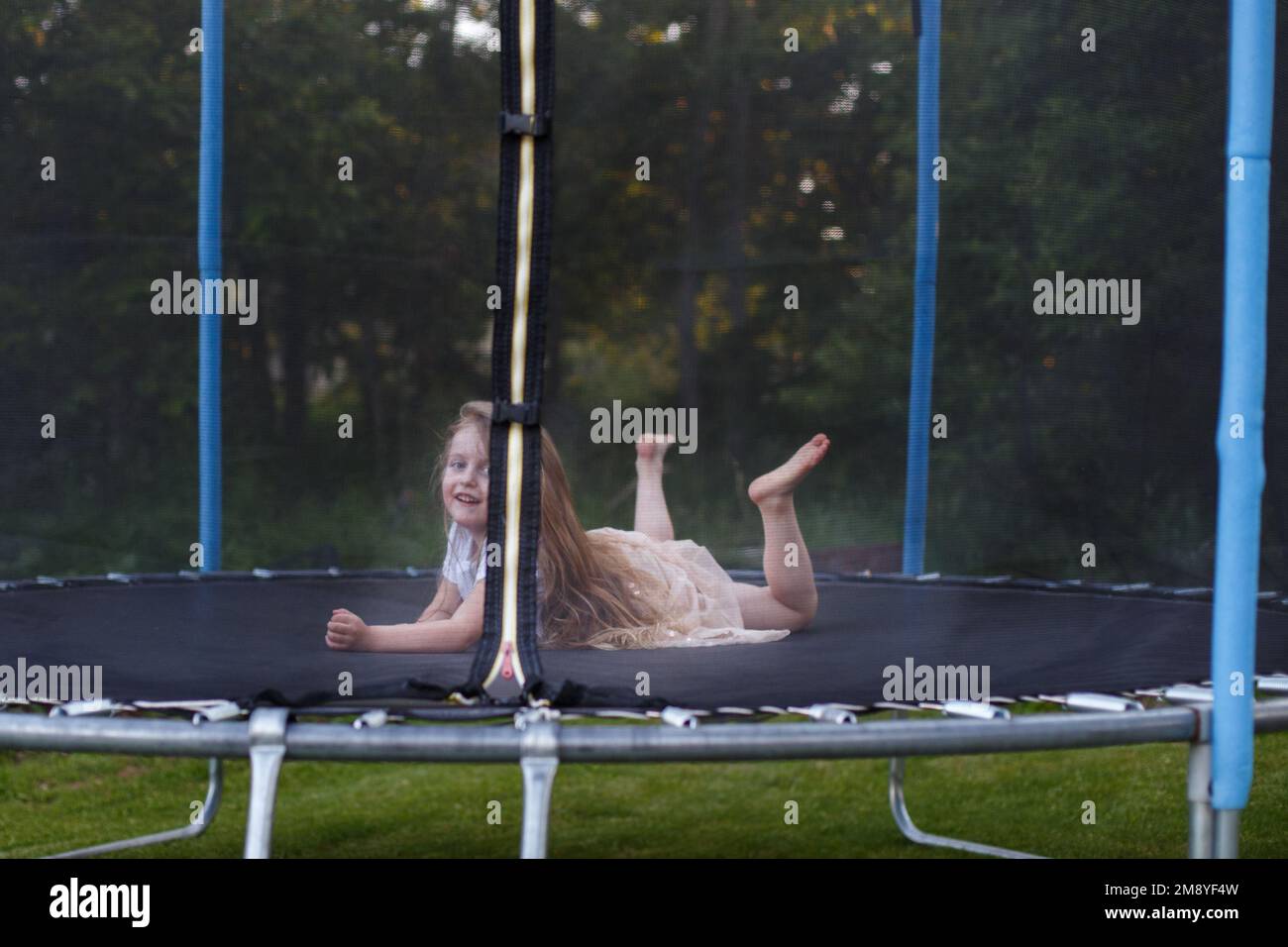 a Little child girl jumping on the trampoline in the back yard Stock Photo