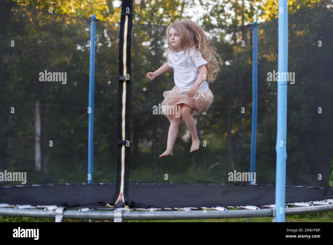 a Little child girl jumping on the trampoline in the back yard Stock Photo