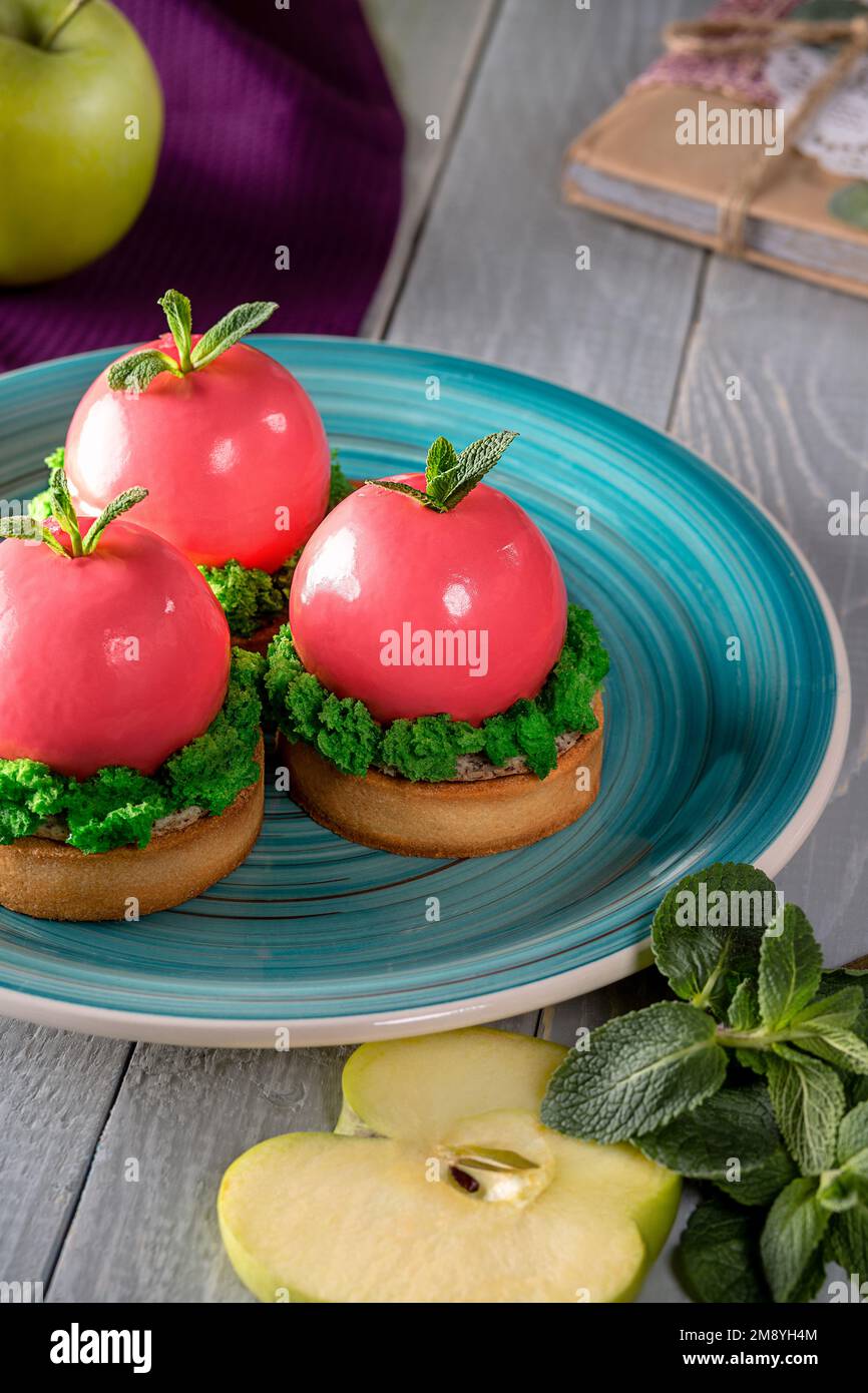 Apple shaped mousse dessert in pink glaze on shortcrust tartlets Stock Photo