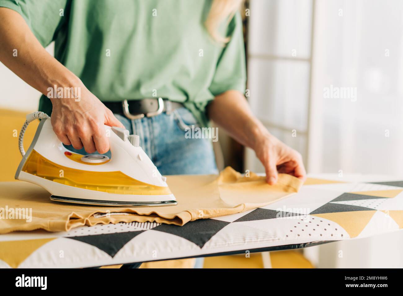 Closeup of an unrecognizable woman ironing clothes with steam on an