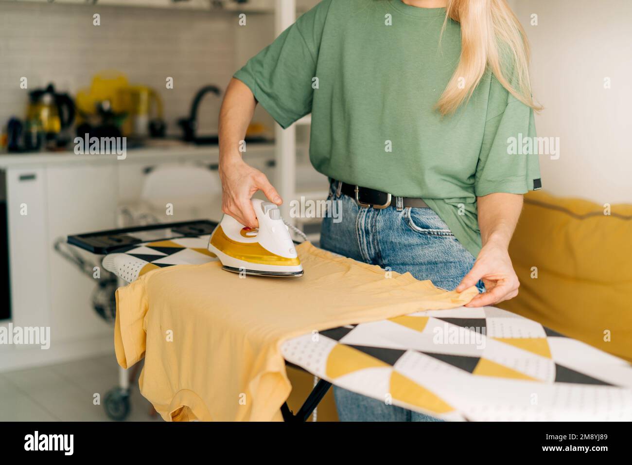 Woman housewife does housework and irons clothes at home. Stock Photo