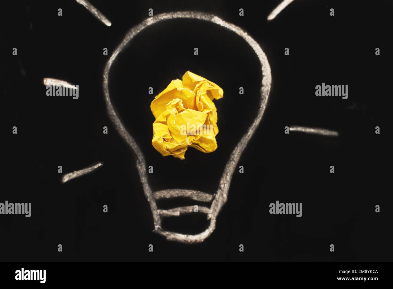 crumpled yelllow paper laightbulb as a concept creative idea and innovation on a blackboard background. Stock Photo