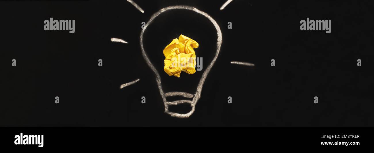 crumpled yelllow paper laightbulb as a concept creative idea and innovation on a blackboard background. banner Stock Photo