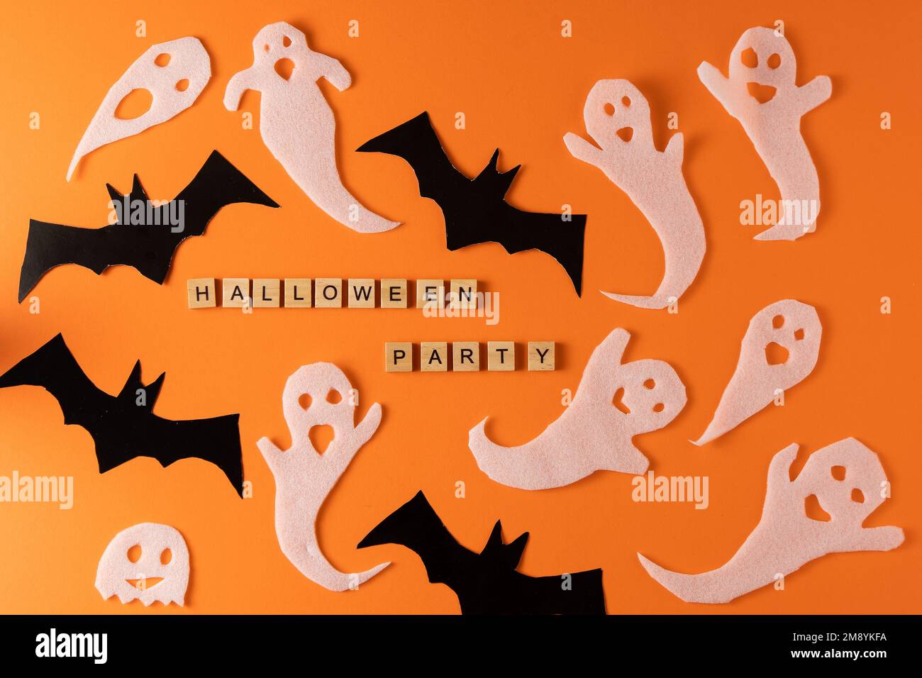 White ghosts and bat craft for Halloween party. Wrapping paper ghost on orange background top view. Cartoon creepy Whisper. DIY hand made. Set boo characters. Word wooden letter phrase. Stock Photo