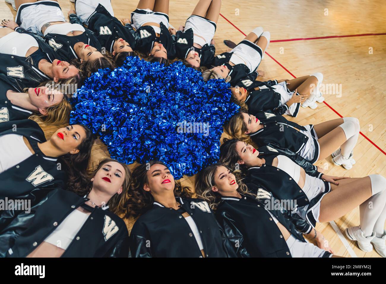 Cheerleaders lying donw in a circle with pom-poms in the middle. Sport concept. High quality photo Stock Photo