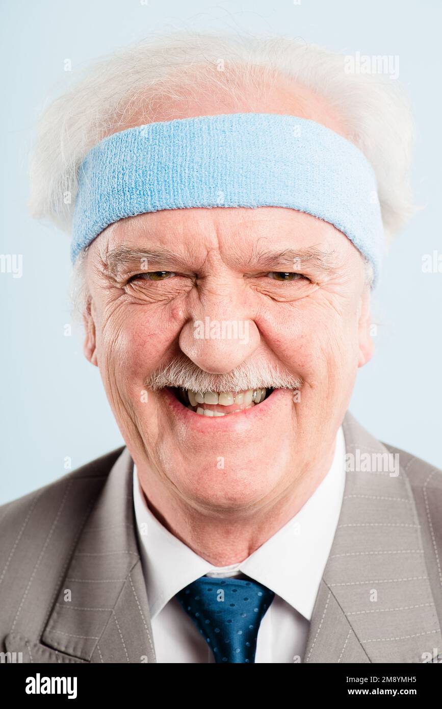 Tell me another joke. a senior man standing alone in the studio and laughing. Stock Photo