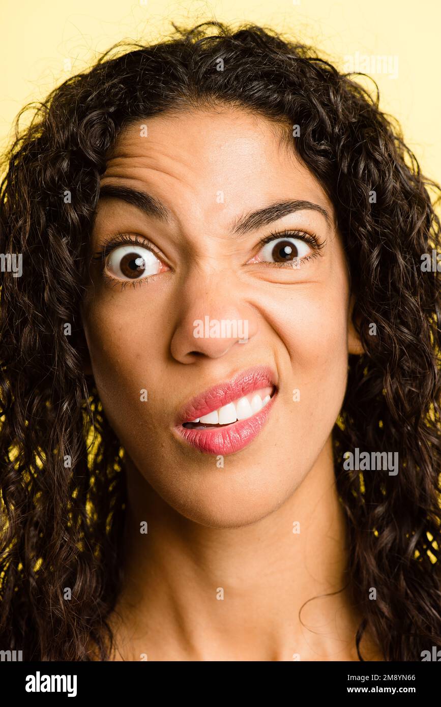 Sorry, what. an attractive young woman standing alone in the studio and pulling funny faces. Stock Photo