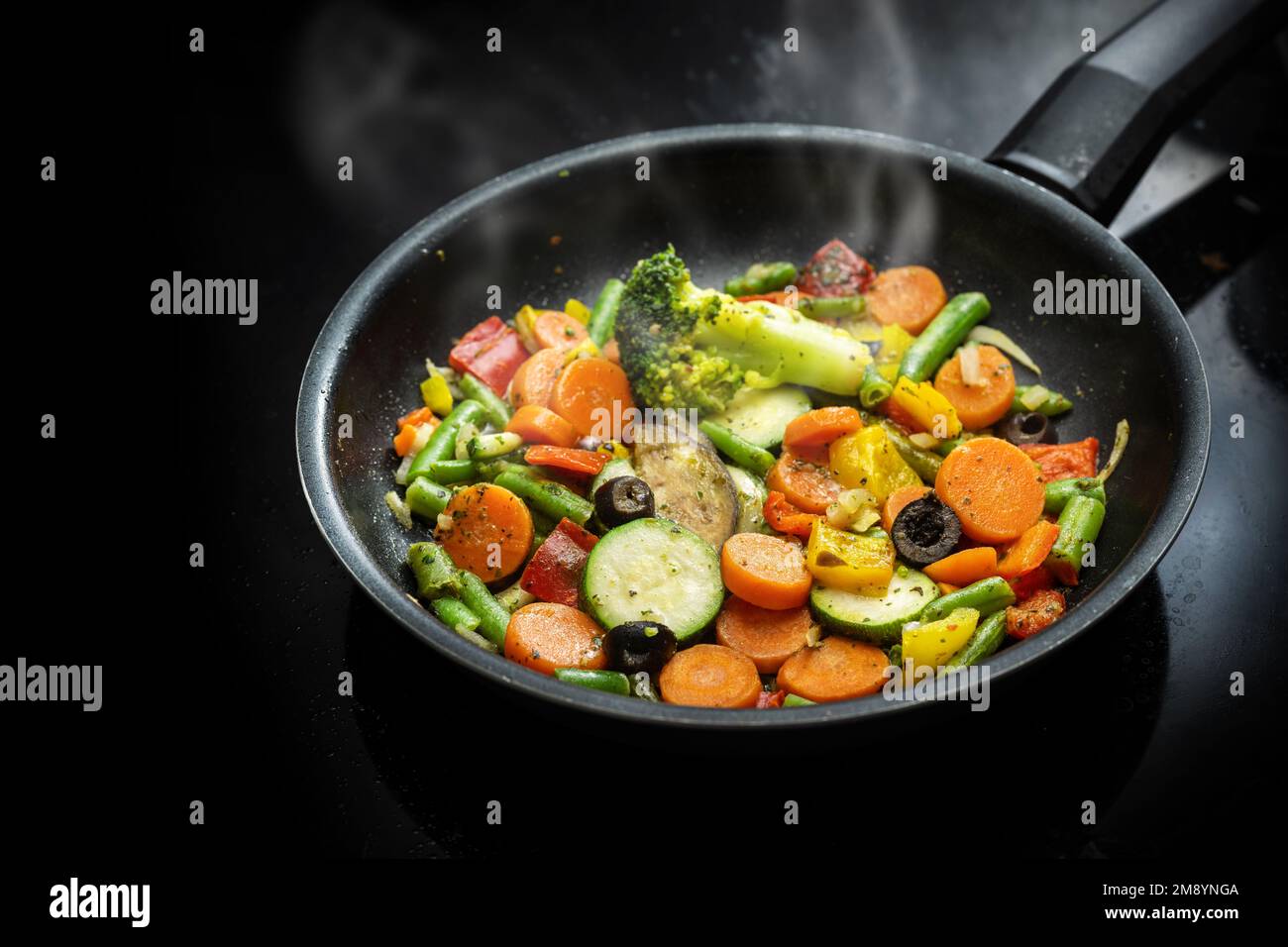 Stir fry vegetables in a black pan with carrots, zucchini, broccoli ...