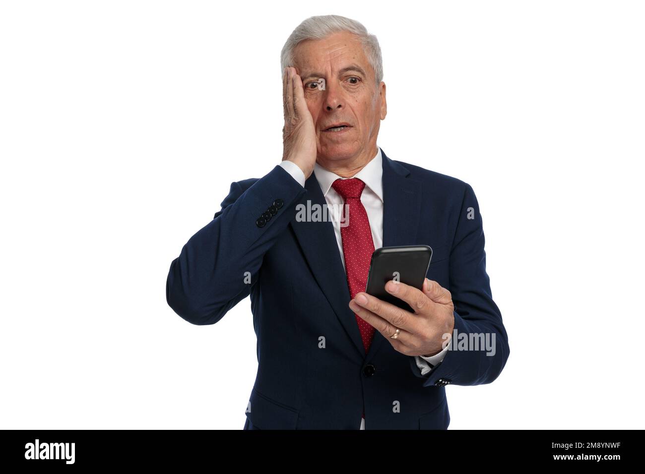 Old businessman feeling anxious to open he's emails on his mobile phone and slapping his face Stock Photo