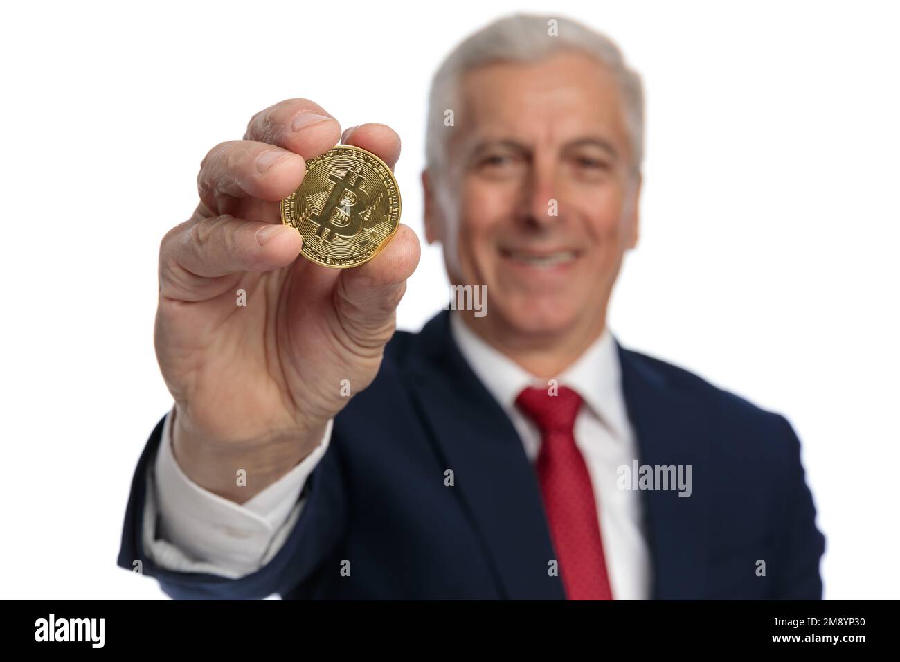 Old businessman presenting a bitcoin at the camera encouraging us to invest in crypto coins Stock Photo